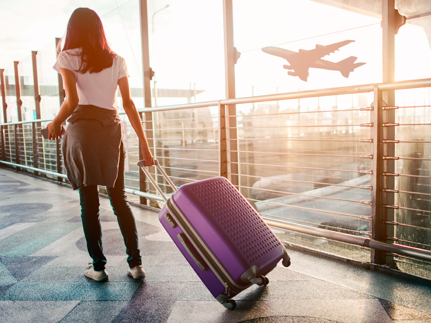 femme avec sa valise dans un aéroport pour illustrer le service de transfert vers les gares et aéroports